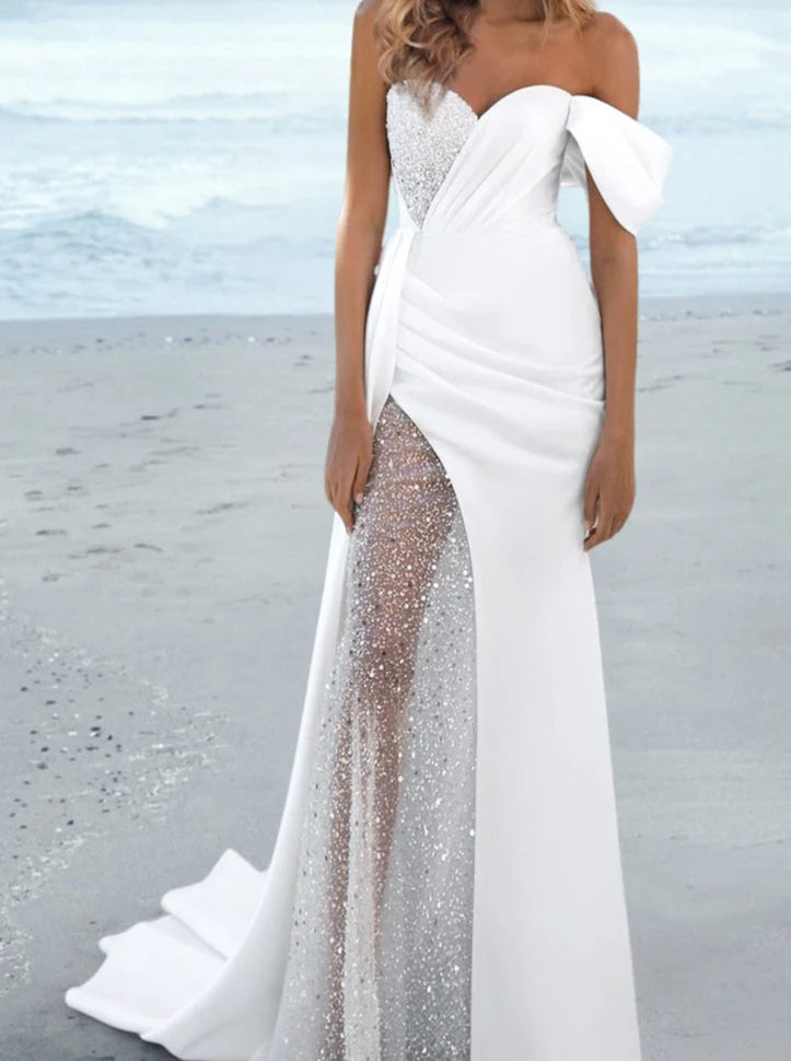 Woman wearing an elegant white one-shoulder floor-length sheath wedding dress.