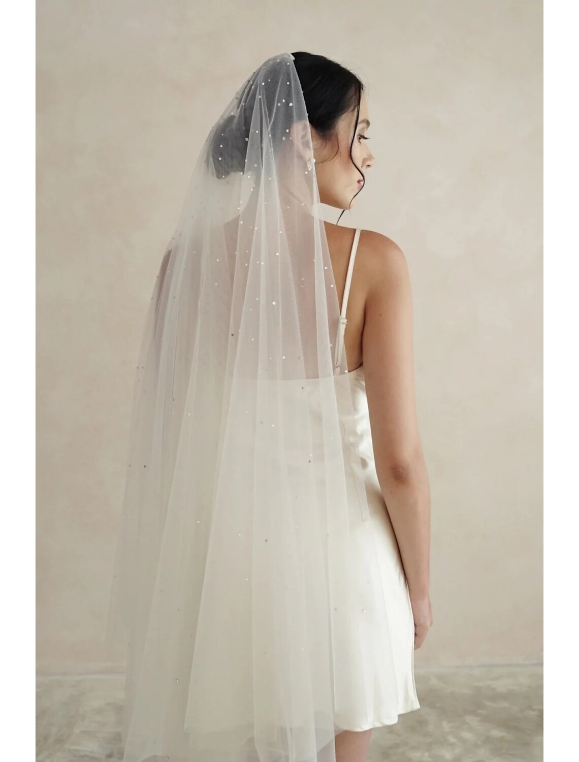 Bride wearing an elegant one-tier chapel wedding veil with sparkling rhinestone and crystal embellishments.