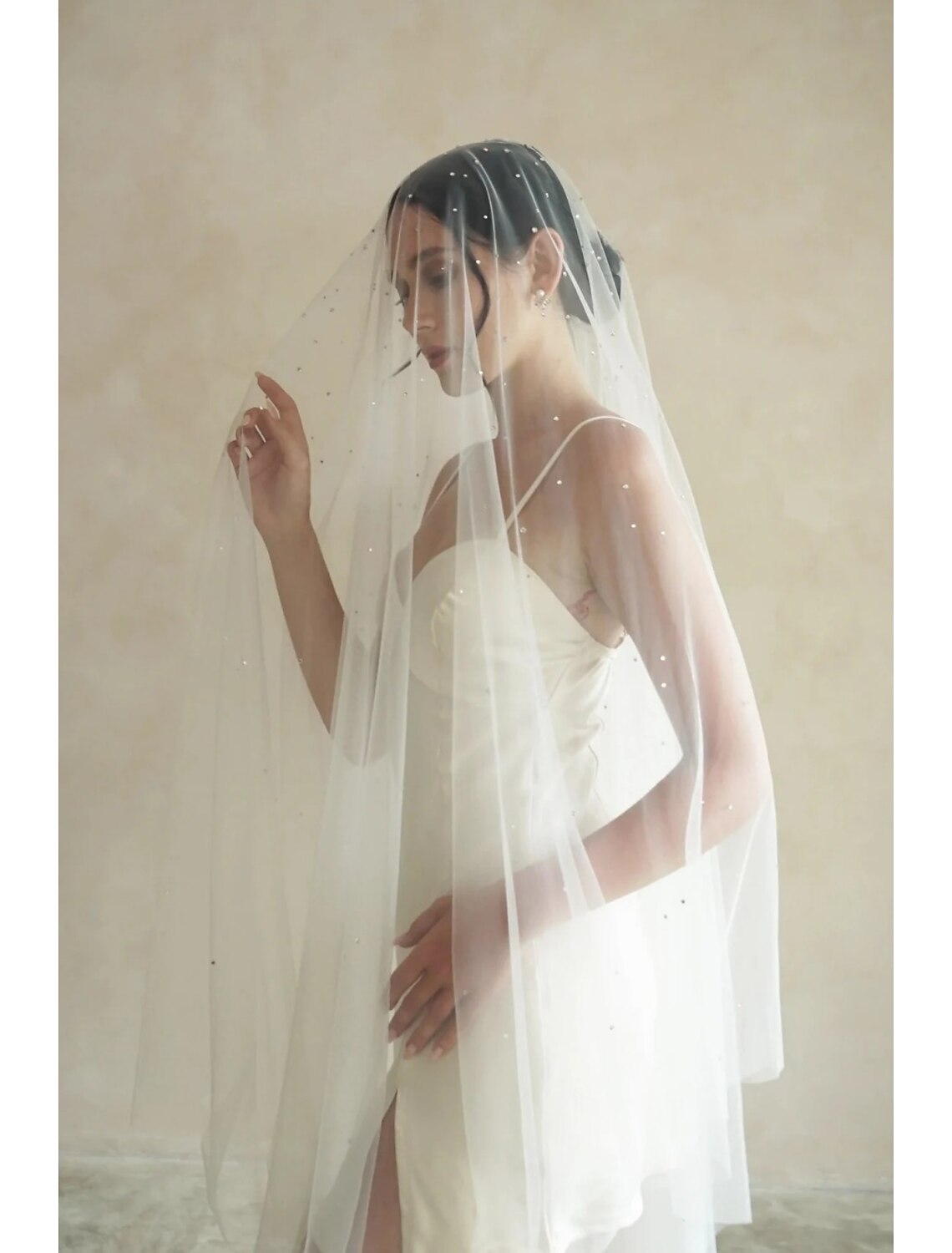 Close-up of the delicate rhinestone and crystal details on the wedding veil's tulle fabric.