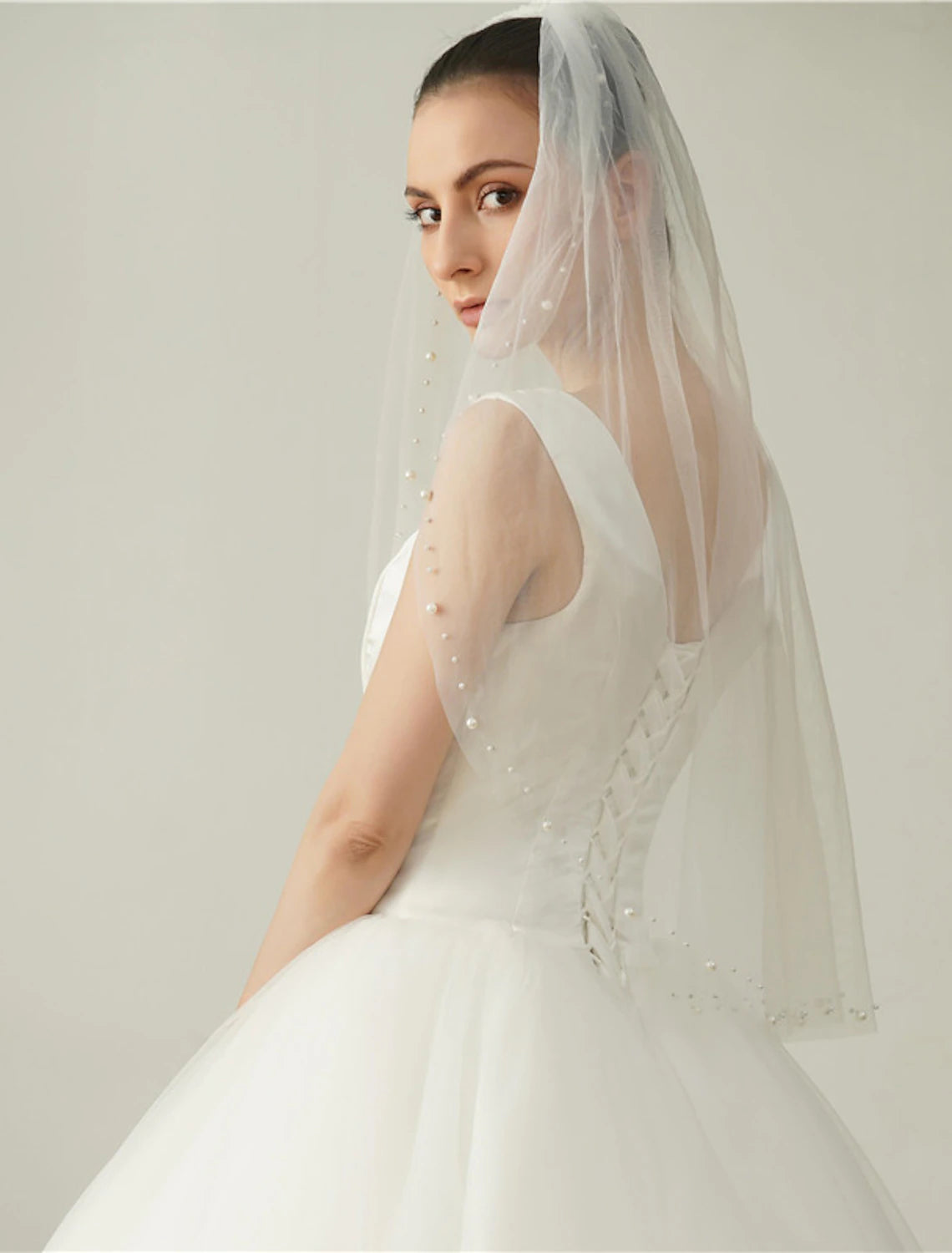 Elegant one-tier elbow wedding veil with faux pearls, draped gracefully.