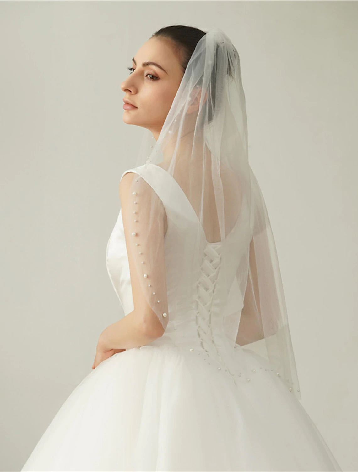 Detail view of the soft tulle fabric and delicate faux pearls on a bridal veil.