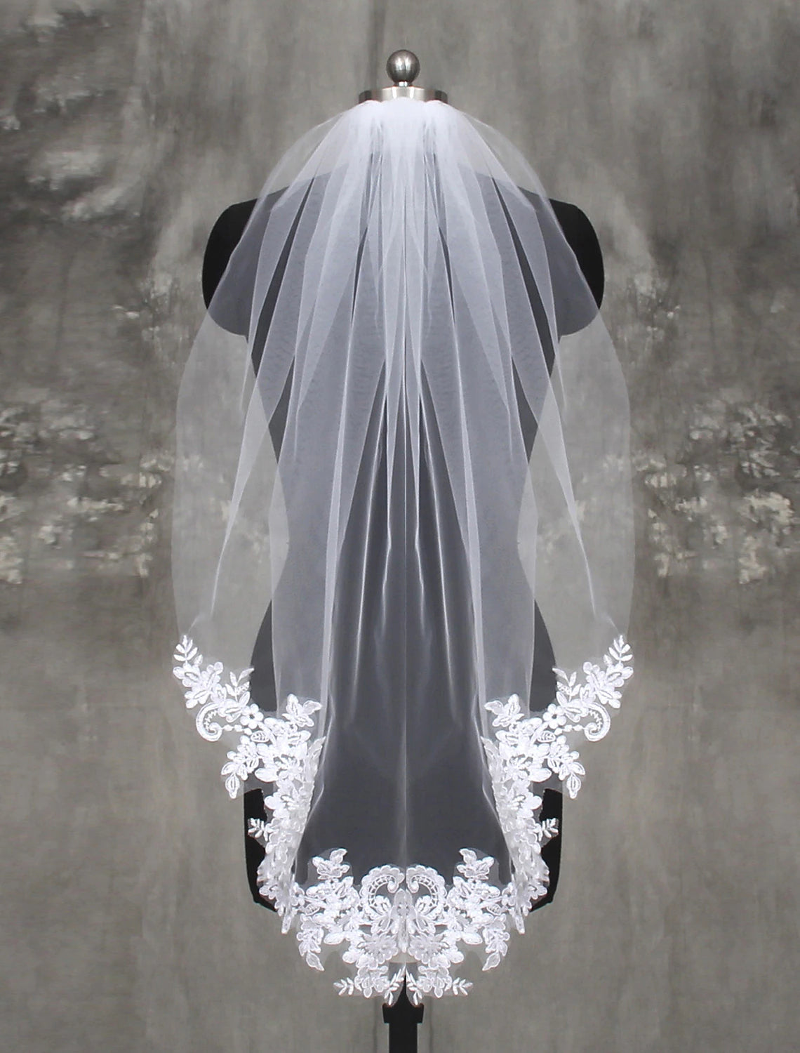 Bride wearing an elegant one-tier fingertip wedding veil with delicate lace appliques.