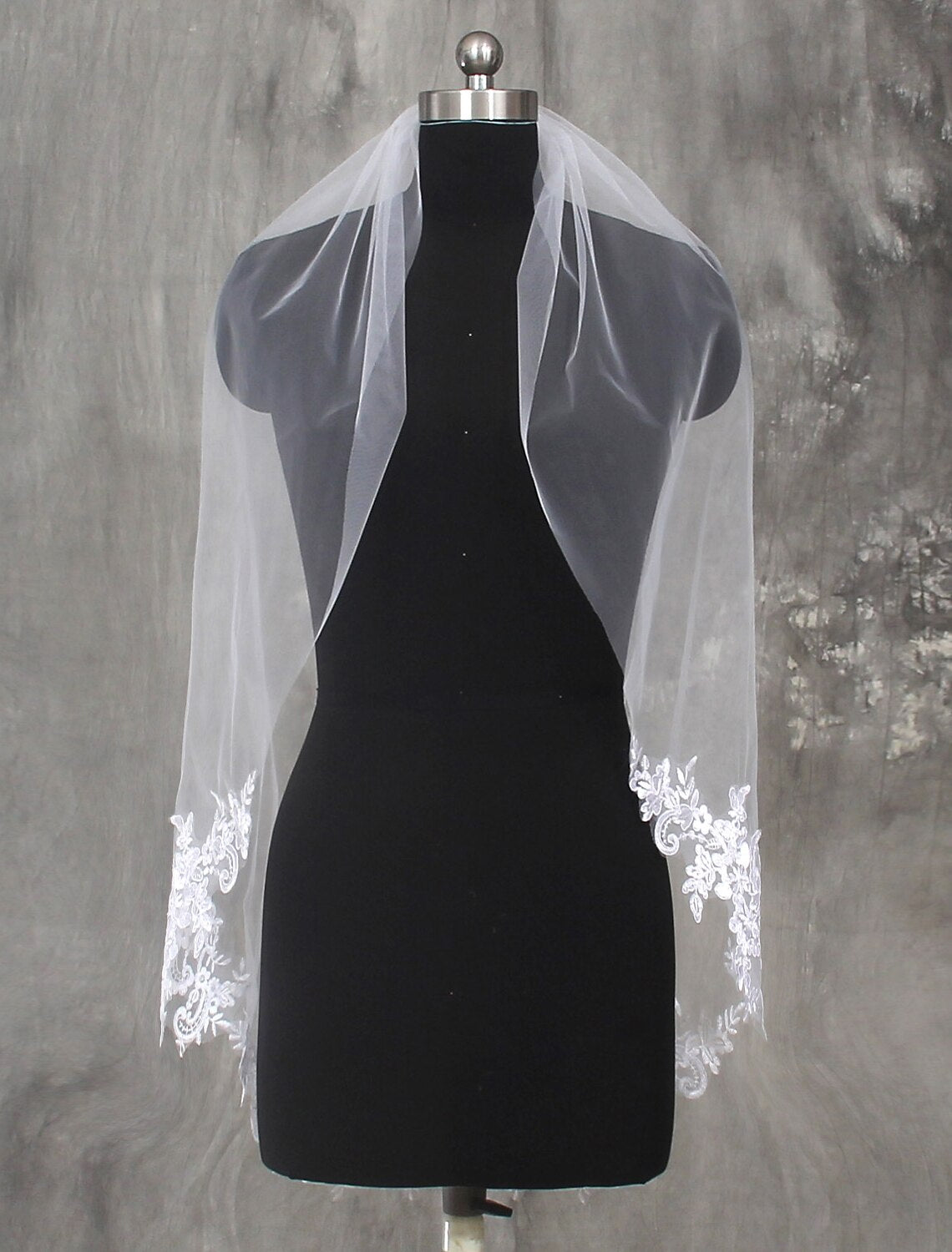 One-tier fingertip wedding veil with lace details, draped to show its full length.