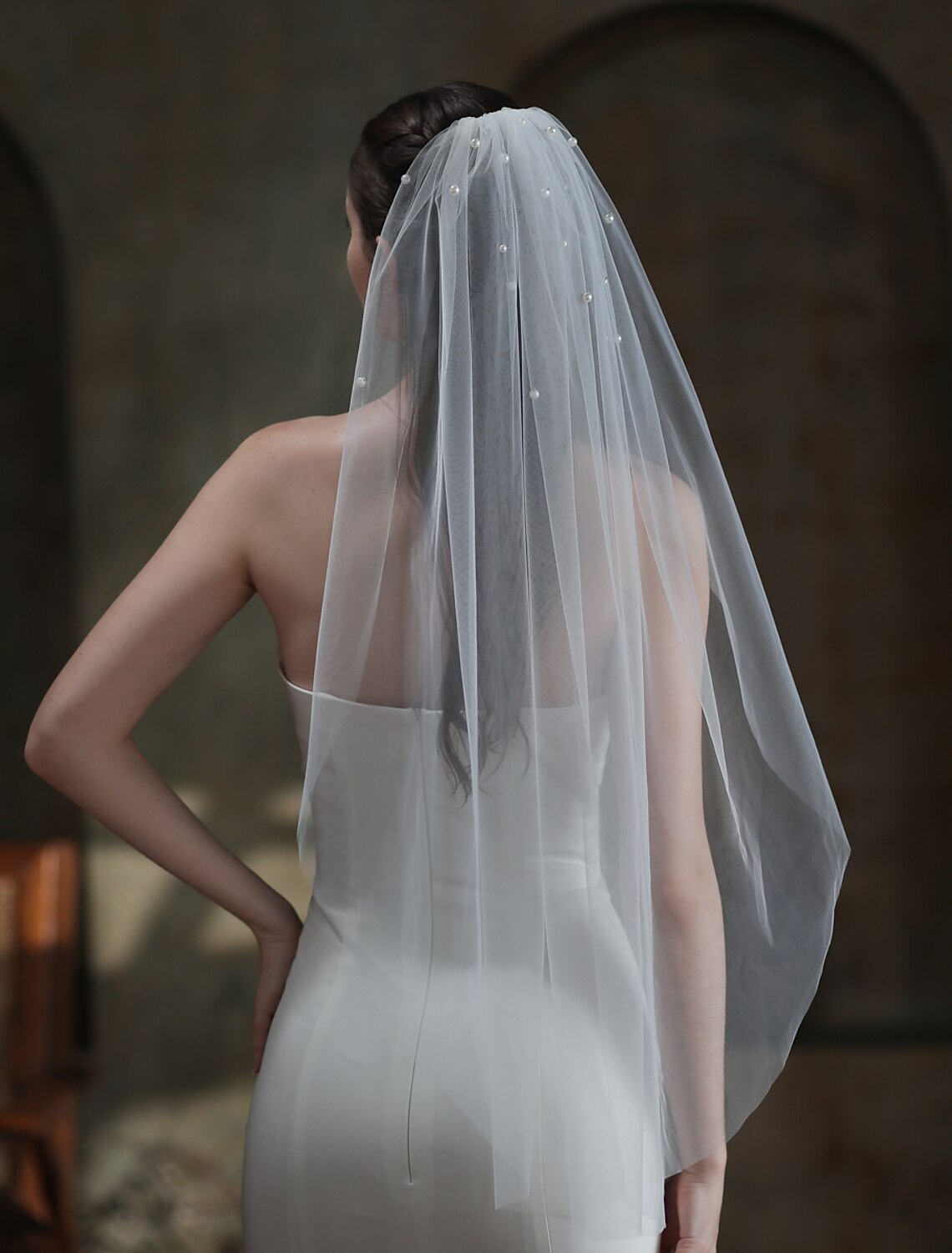 Side view of a bride showcasing a one-tier tulle wedding veil with pearls.