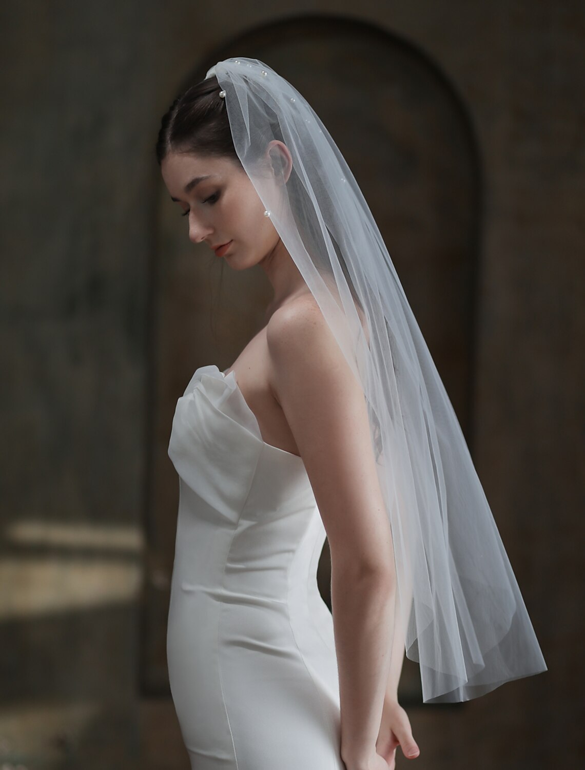 Fingertip wedding veil with faux pearls draped gracefully.