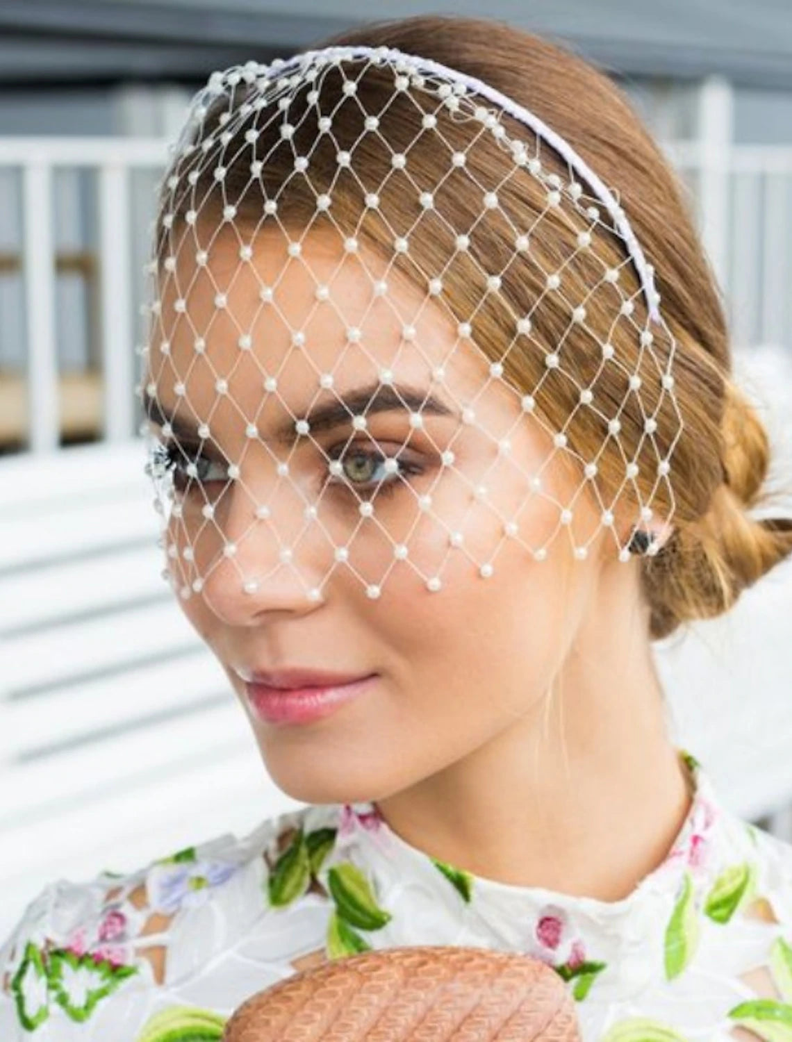 A bride wearing an elegant one-tier wedding veil with faux pearls.