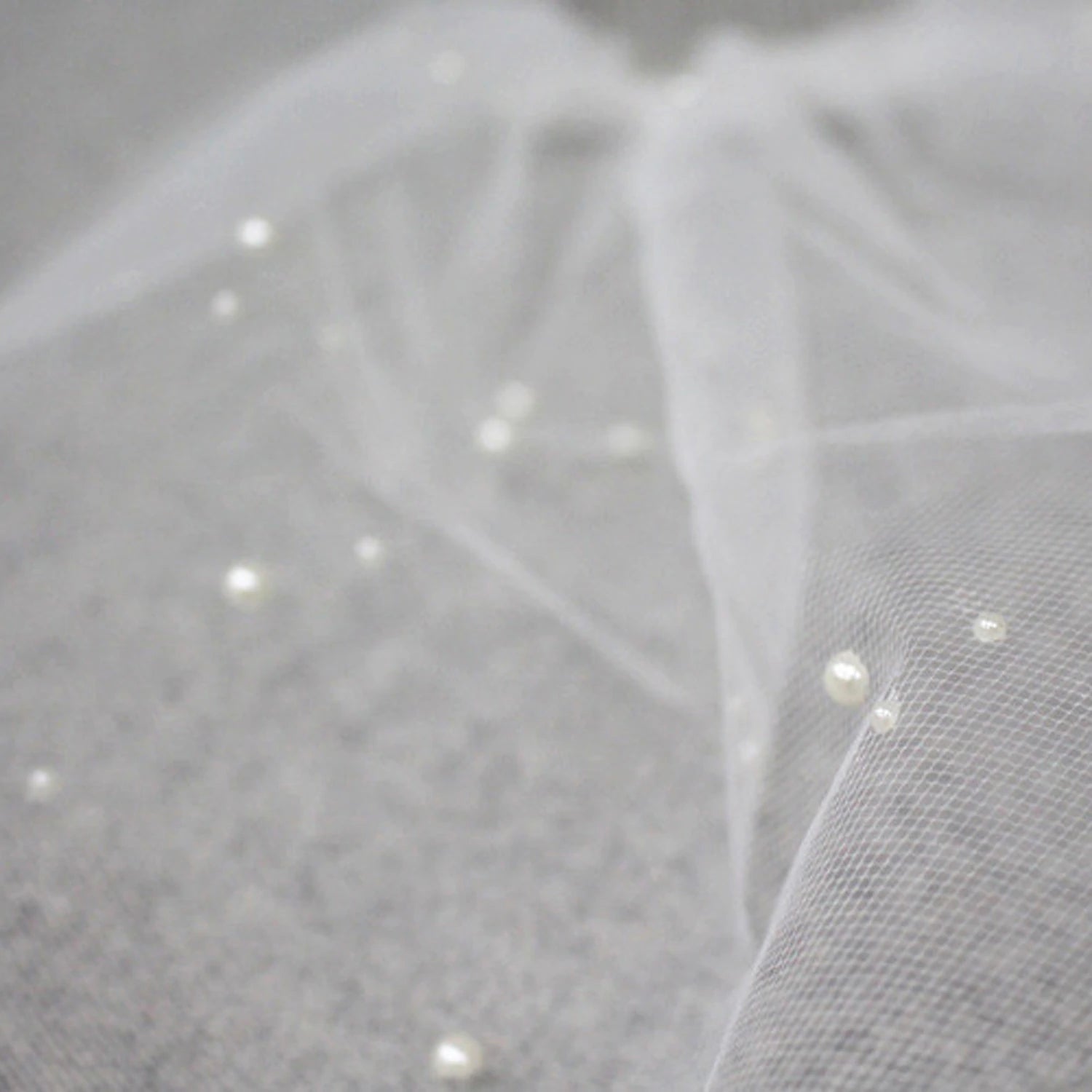 Bridal model wearing a short birdcage wedding veil with pearls.