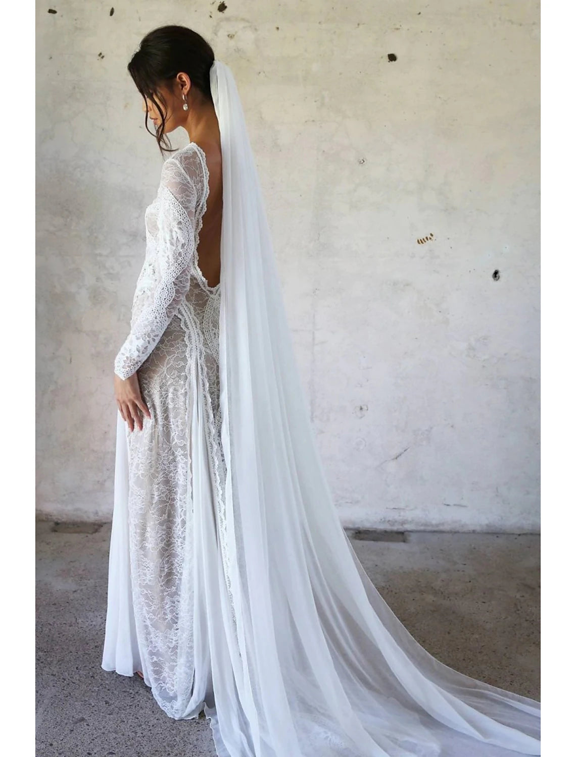 Bride wearing a long, one-tier chiffon cathedral wedding veil.
