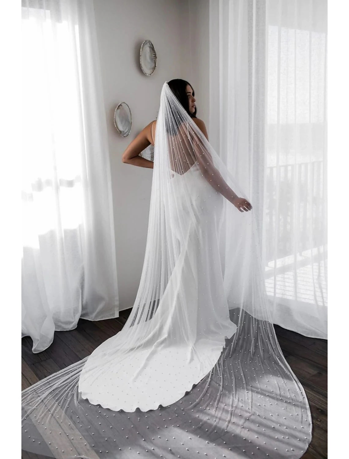 Bride wearing a long tulle wedding veil adorned with pearls.