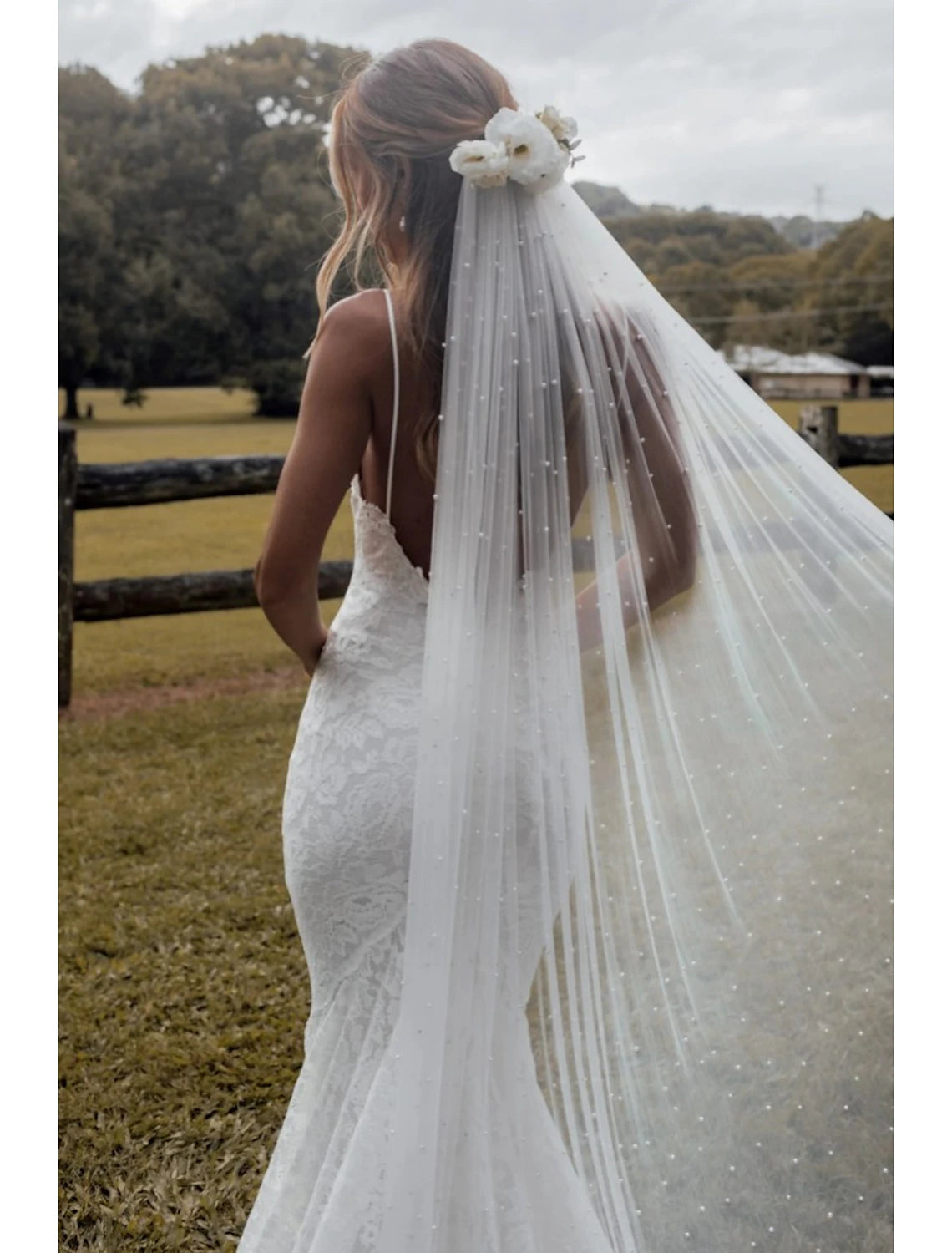 Side profile of a bride showcasing her pearl-embellished wedding veil.