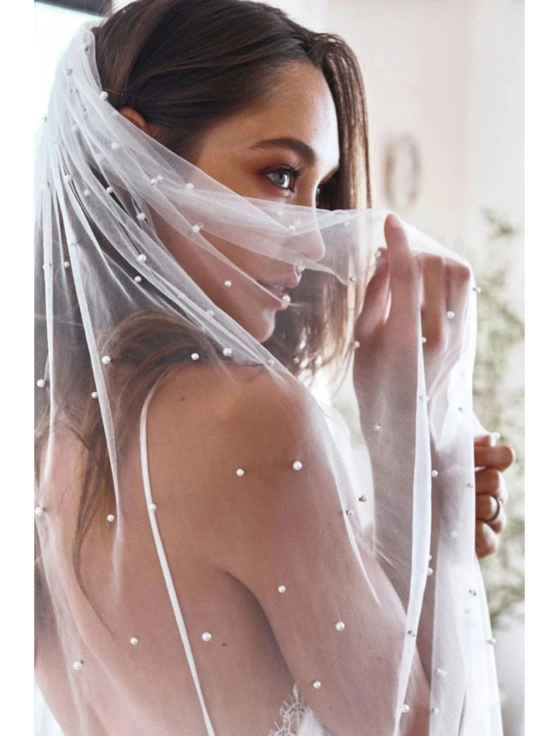 Full length view of a bride in an elegant one-tier pearl wedding veil.