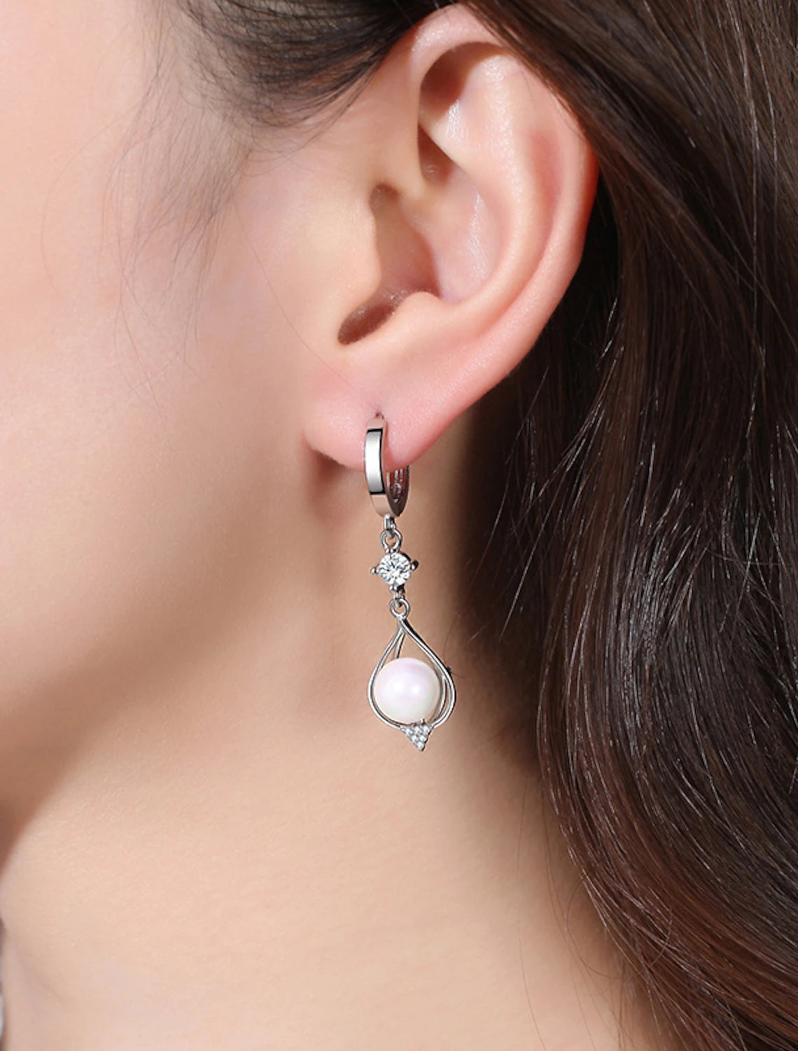 Close-up of a woman wearing classic pearl drop earrings.
