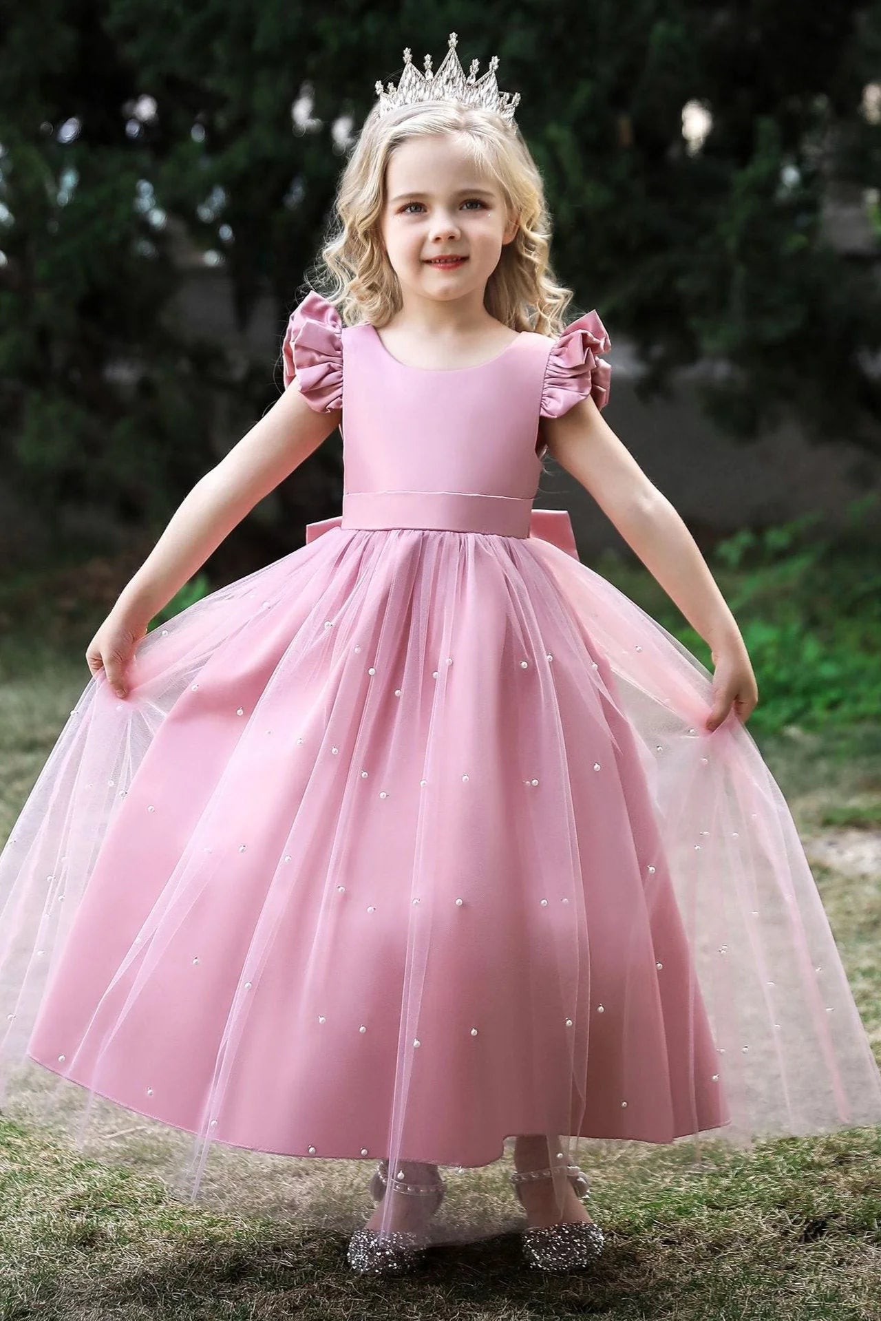 Girl wearing an elegant white flower girl dress with a pearl tulle cape.