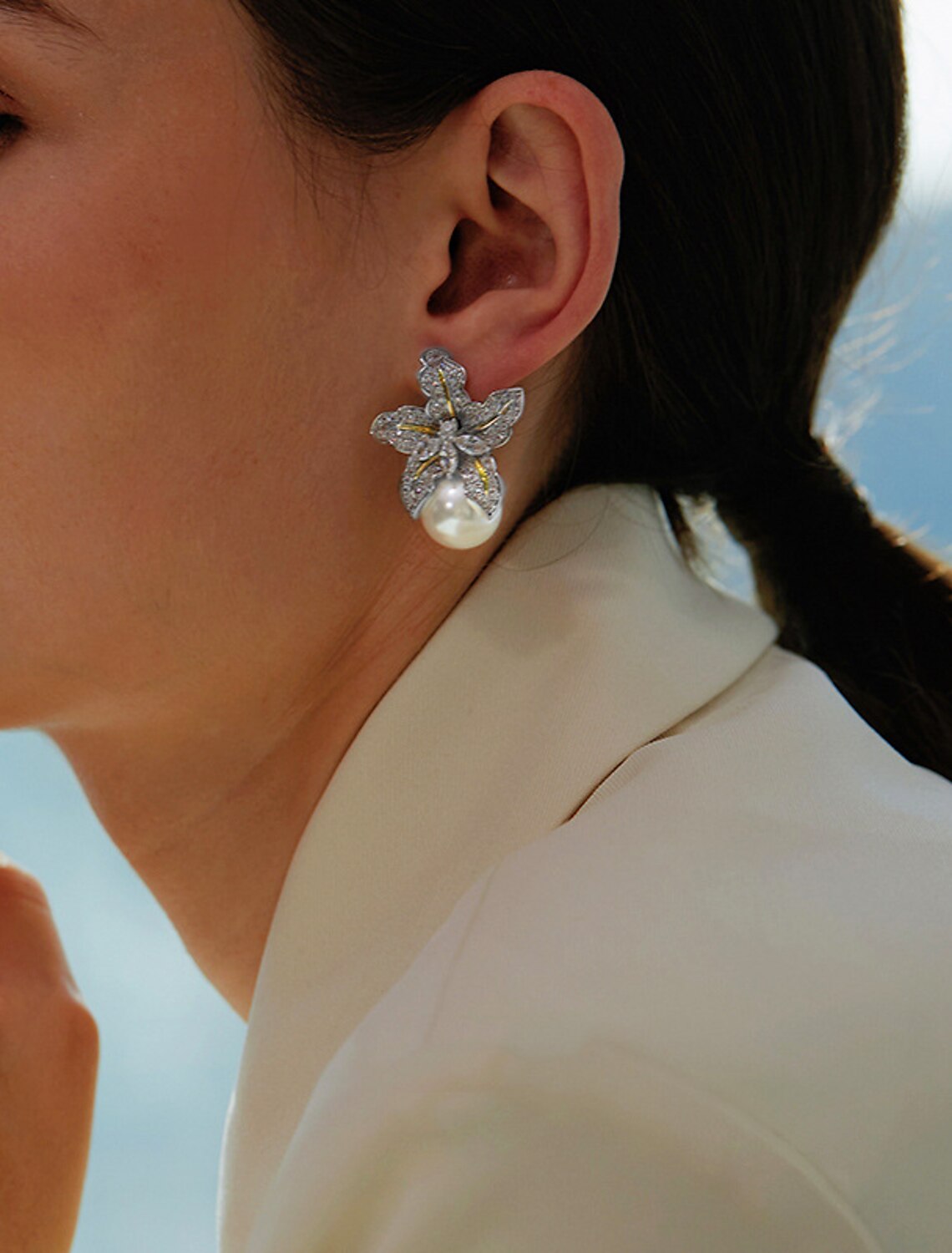 Pair of gold and white petal stud earrings on a display.