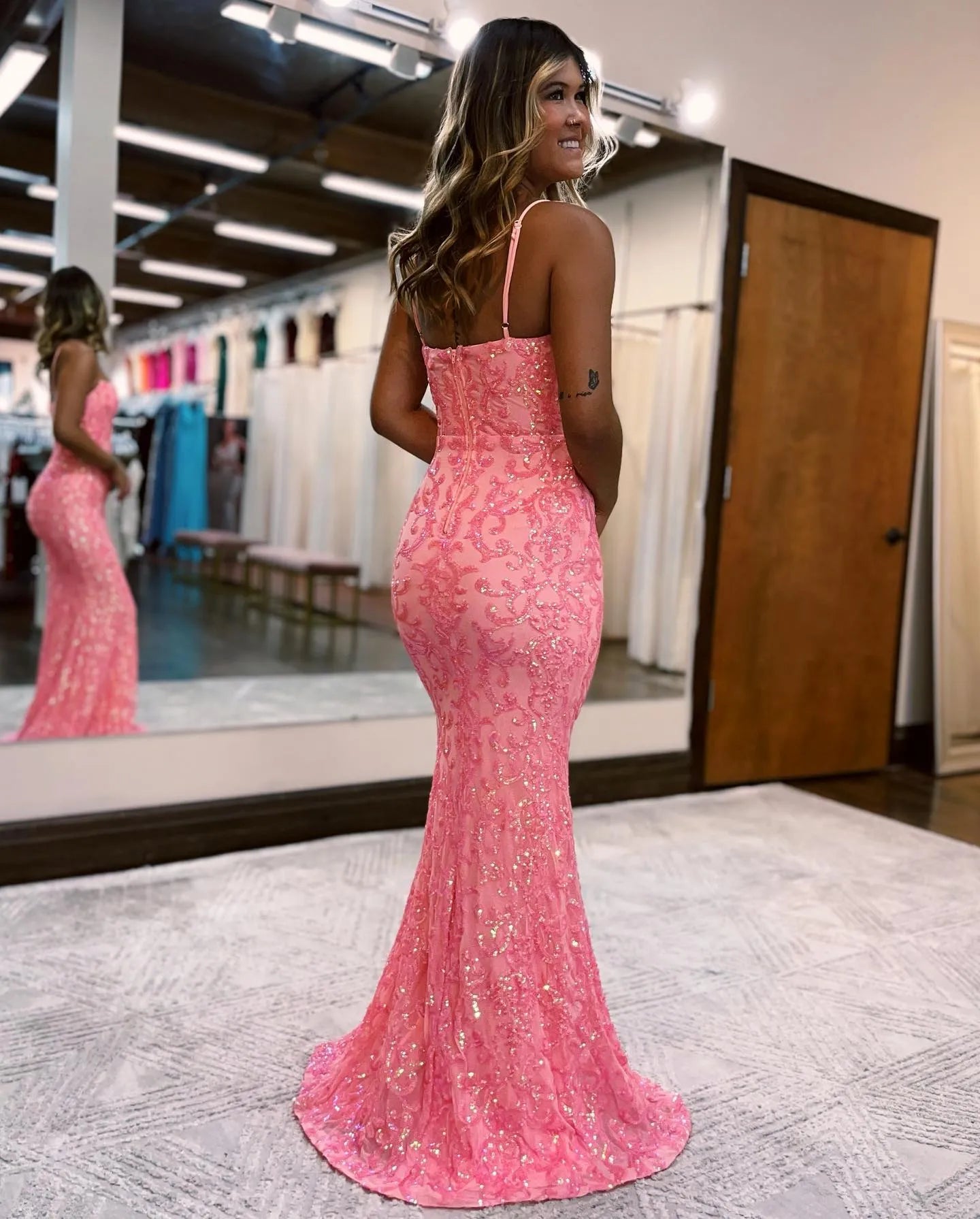 Back view of a pink beaded mermaid gown with delicate spaghetti straps.