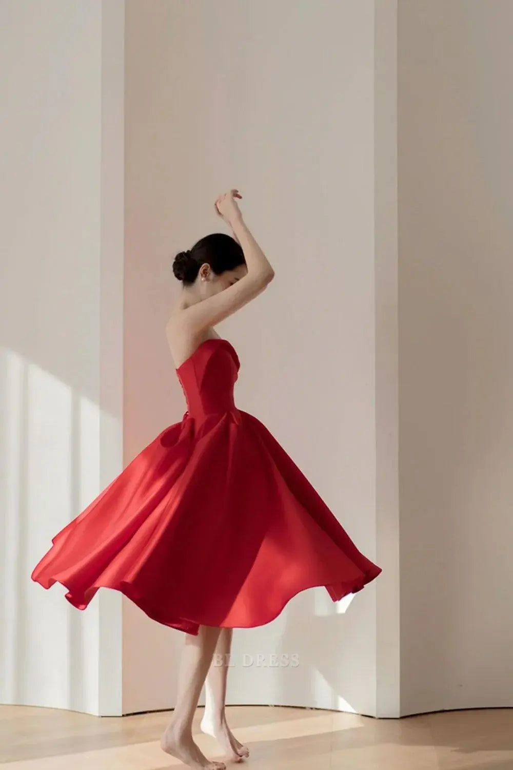Elegant red A-line strapless pleated dress, side view.