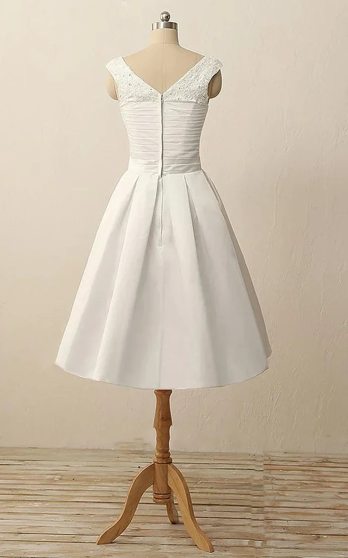 Side view of a woman wearing the V-neck pleated satin dress, showcasing the flowing skirt.
