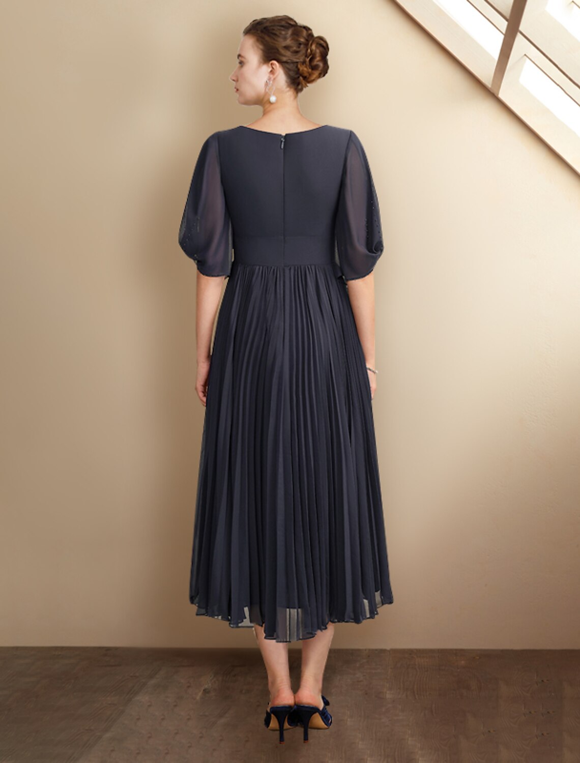 Back view of a tea length chiffon Mother of the Bride dress with pleats.