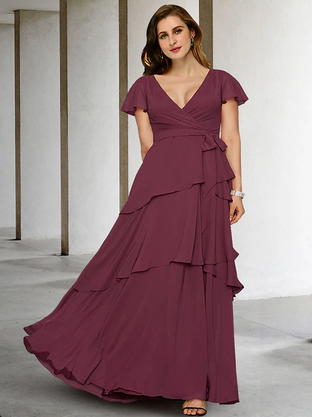 Plus size woman wearing an elegant A-line V-neck chiffon mother of the bride dress with short sleeves and ruffles.