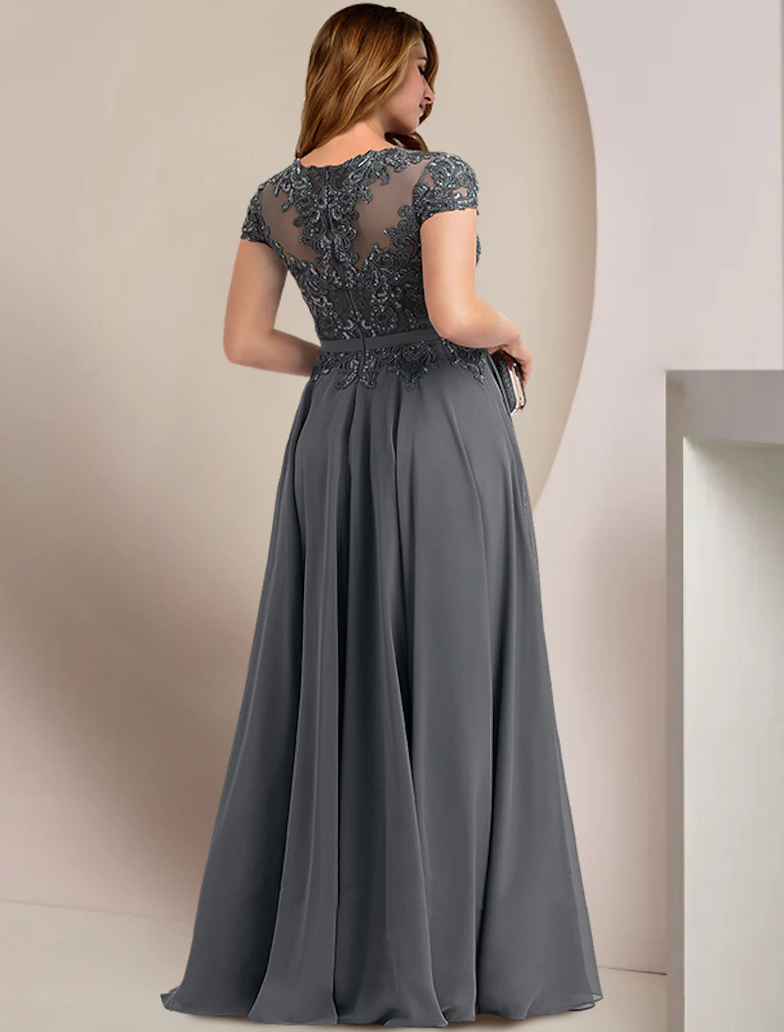 Side view of an elegant plus size wedding guest dress in chiffon and lace.