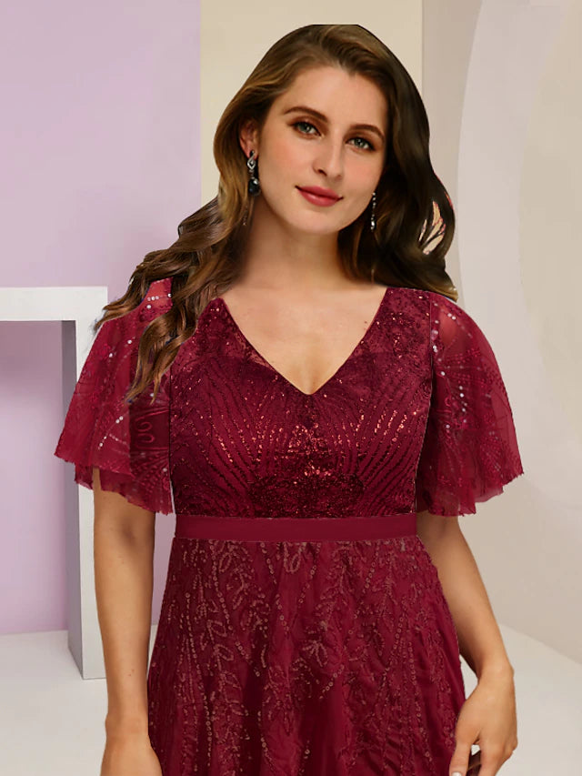 Elegant plus size sequined V-neck gown with a split front, worn by a woman posing.