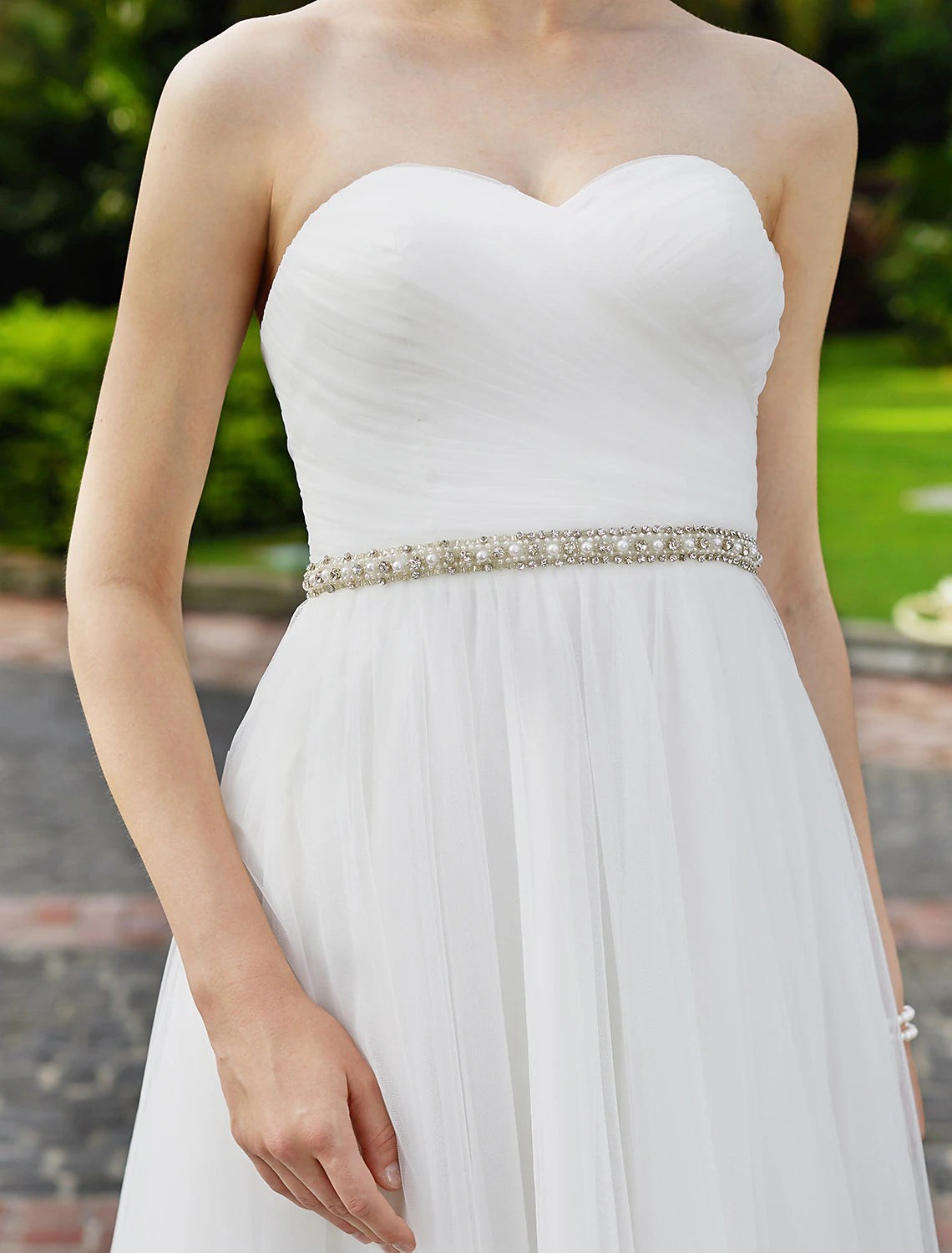 Close-up of beading and sash on a chiffon wedding gown.