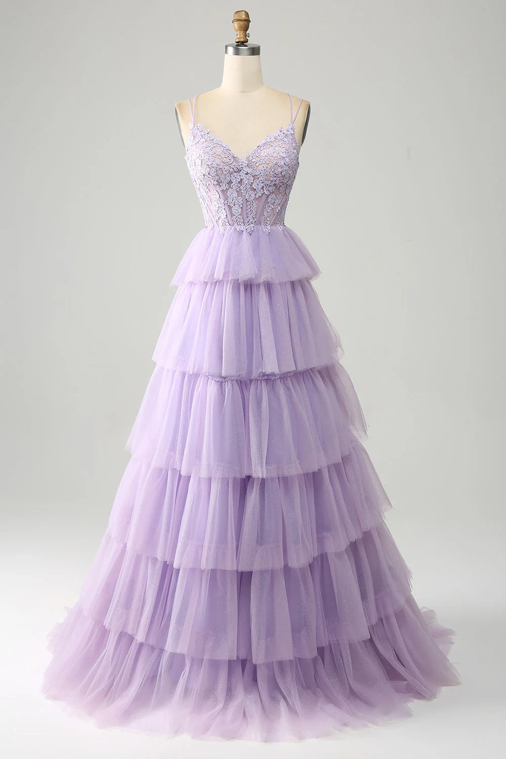 Model wearing a lilac princess prom dress with a corset bodice and tiered tulle skirt, adorned with appliques.