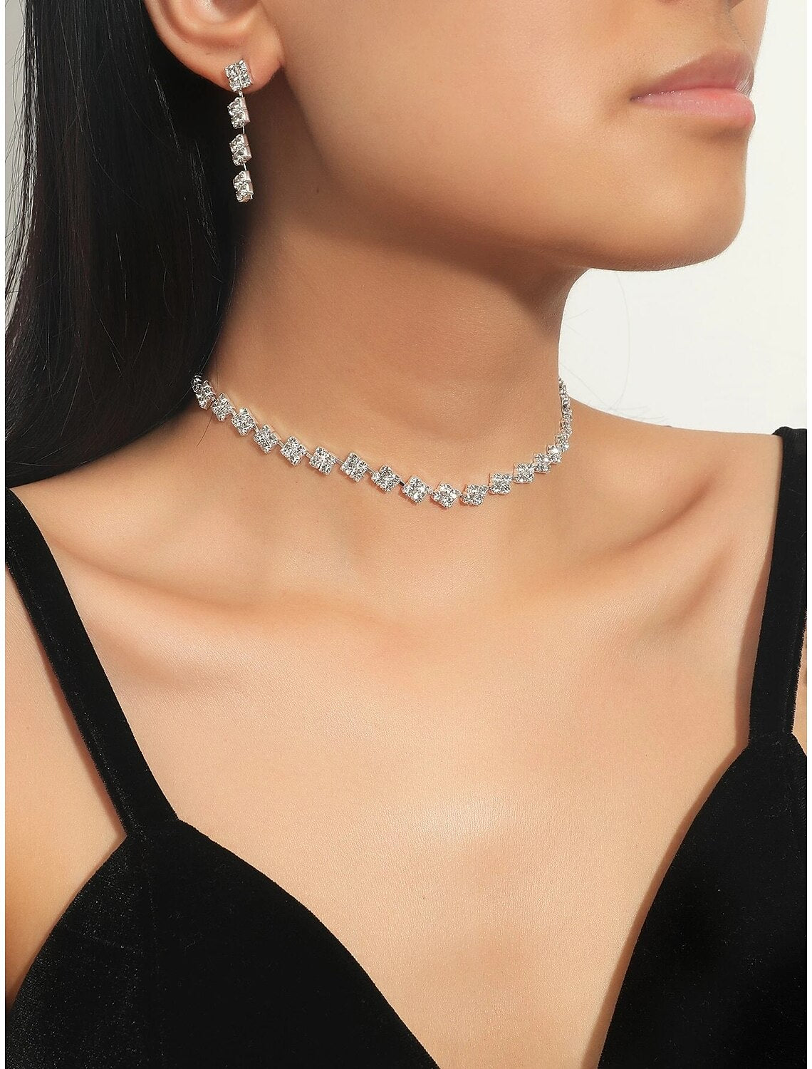 Woman wearing an elegant rhinestone alloy necklace and matching earrings.