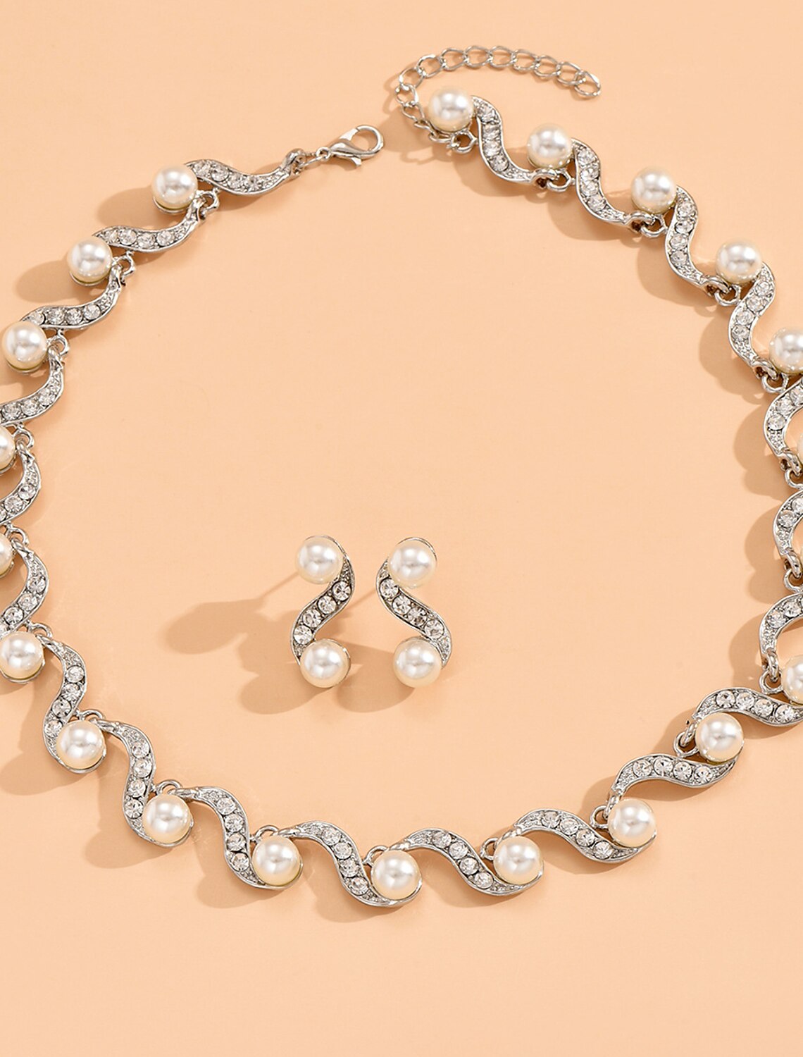 Woman wearing an elegant rhinestone bridal necklace and matching earrings, showcasing the complete set.