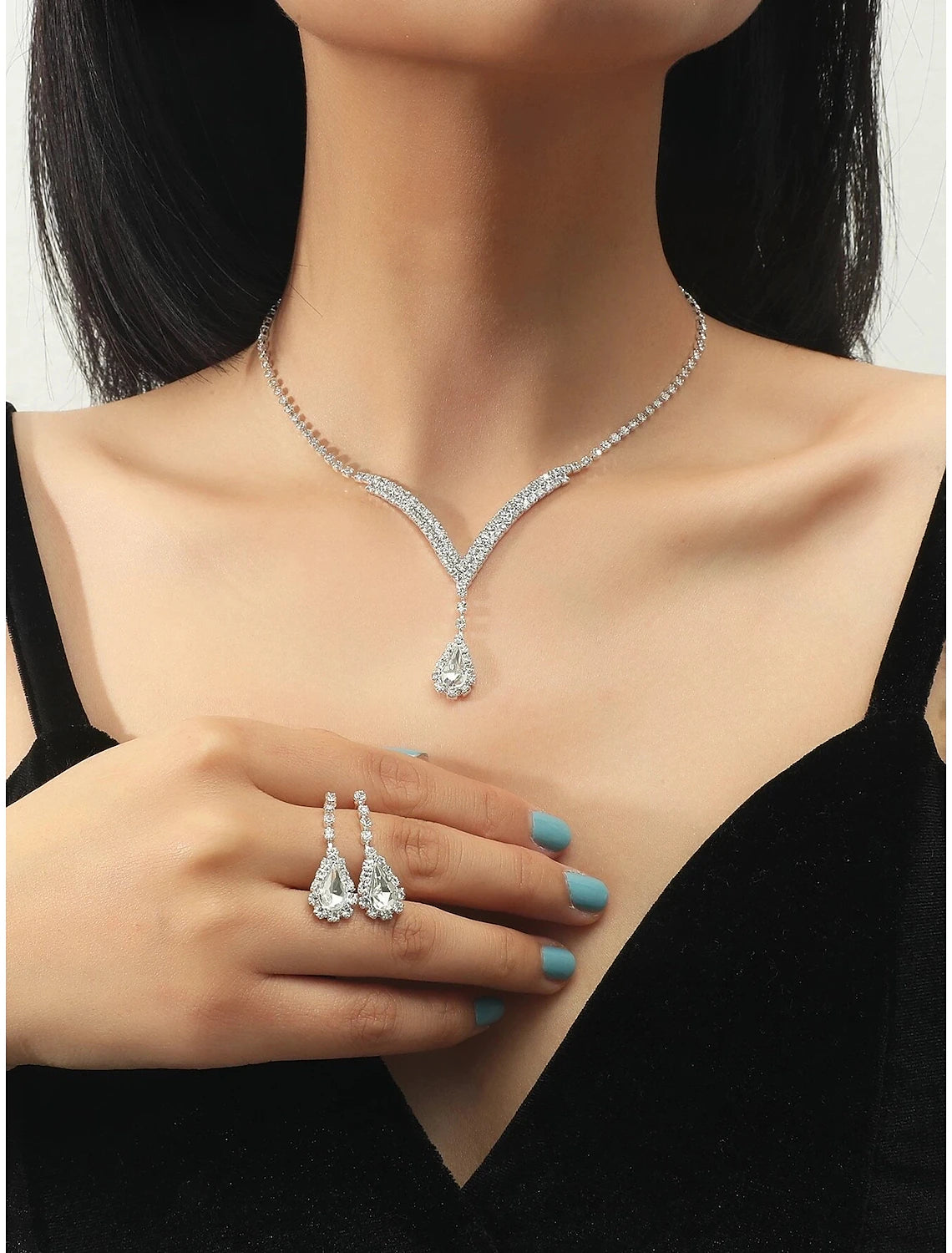 Woman wearing a rhinestone chandelier necklace and matching earrings.