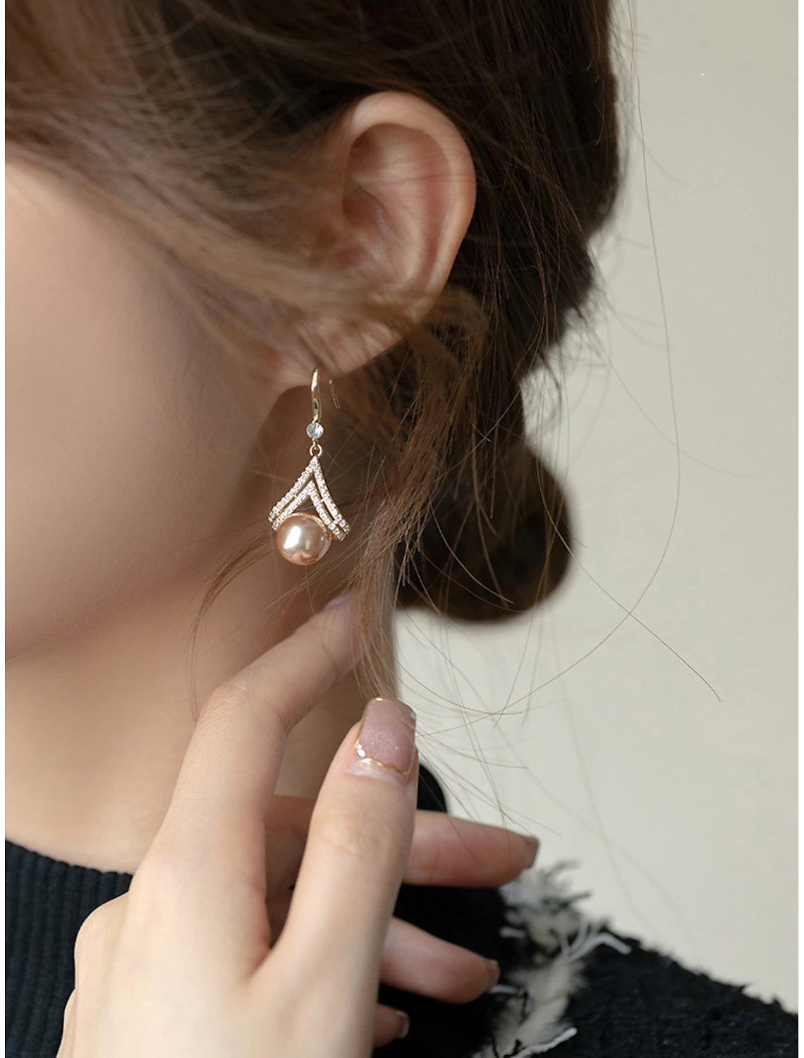Woman wearing a rose gold pearl stud earring.
