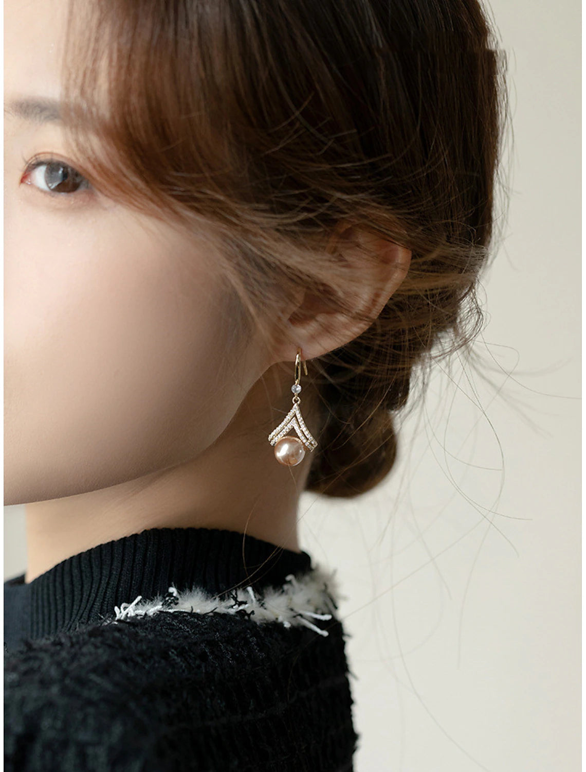 Detailed view of a rose gold pearl stud earring.
