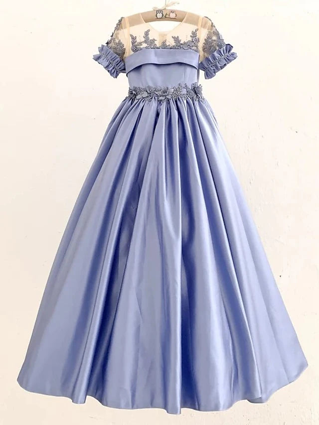 Young girl wearing an elegant white satin ball gown with delicate appliques.