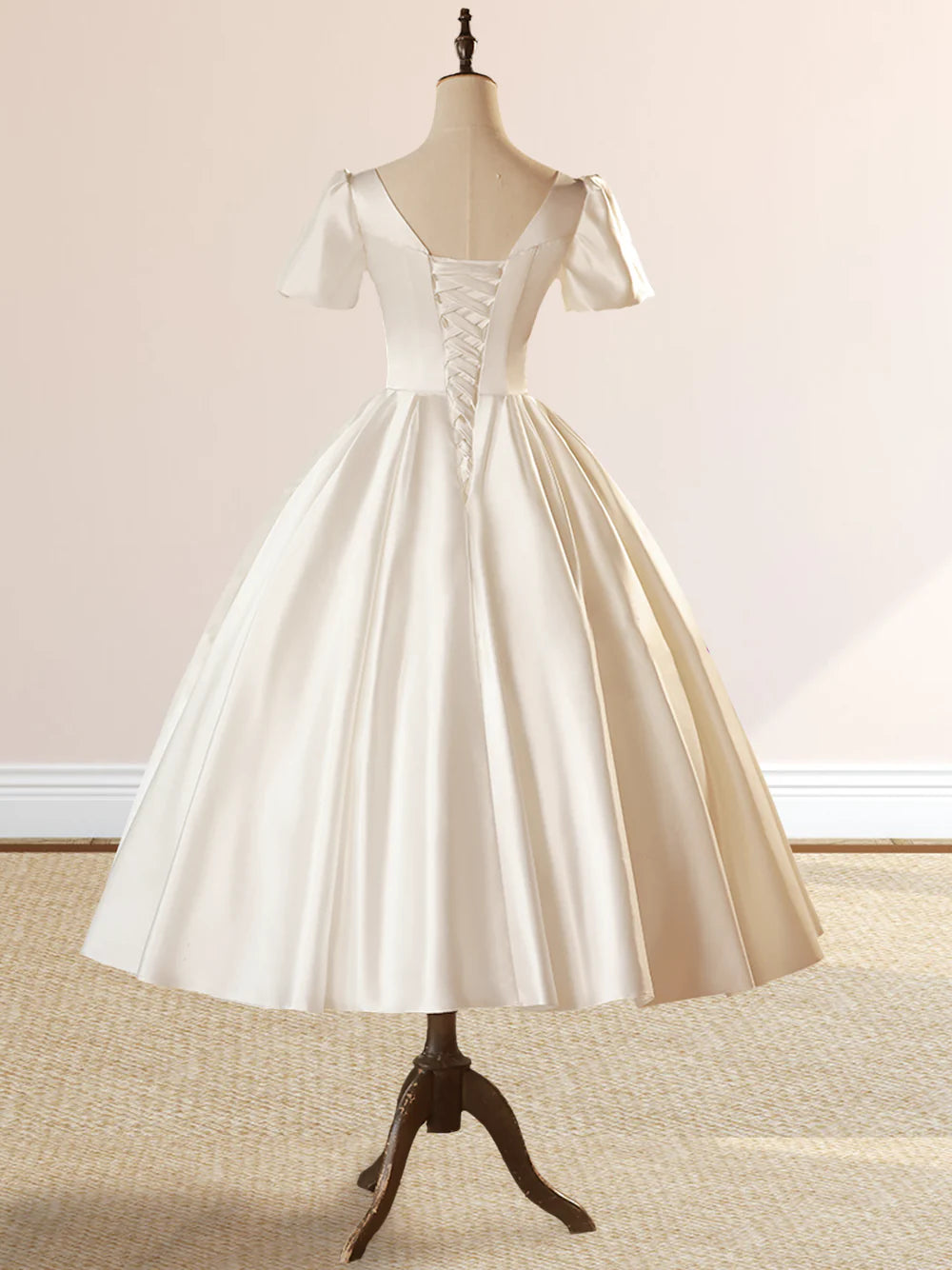 Side view of the white satin wedding dress, highlighting the short sleeves and flowing skirt.