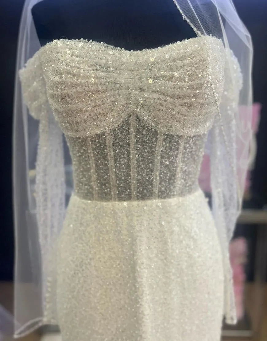 Close-up of sequin details on off-shoulder wedding dress.