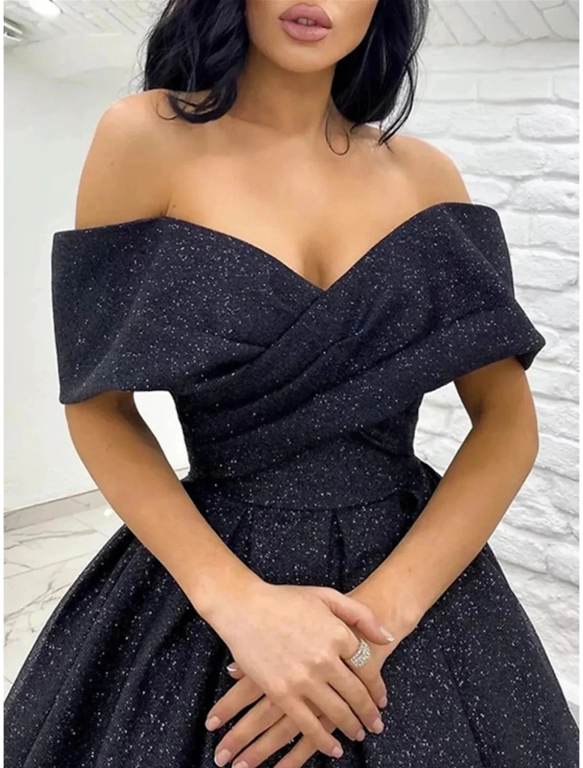 Detail of the off-shoulder neckline and short sleeve on the sequined dress.