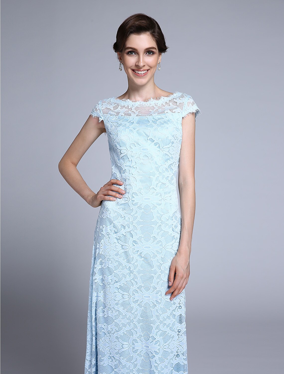 Close-up of the delicate lace fabric and bateau neckline on the dress.