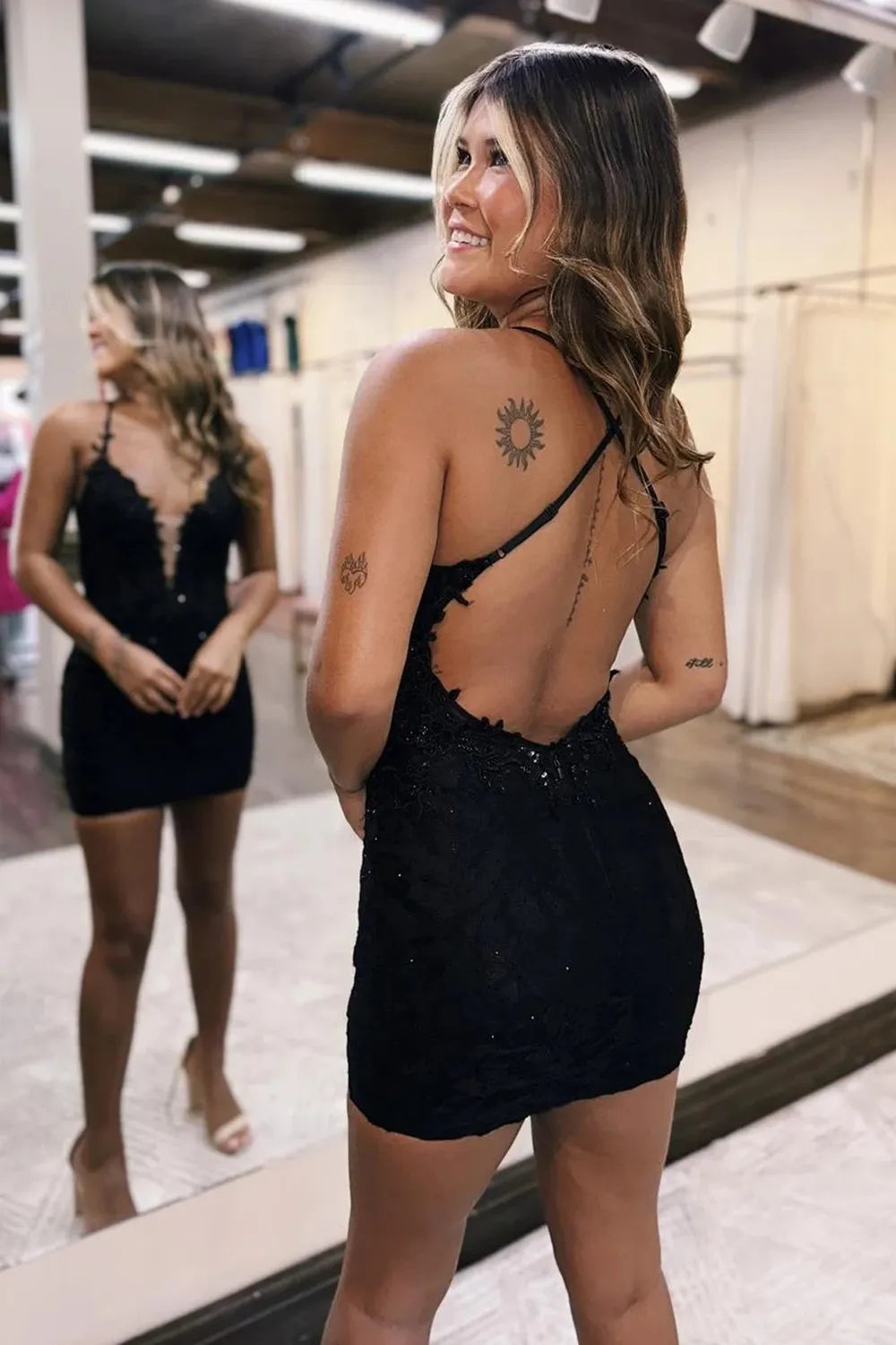Close-up of the black bodycon dress, highlighting the spaghetti straps and applique details.
