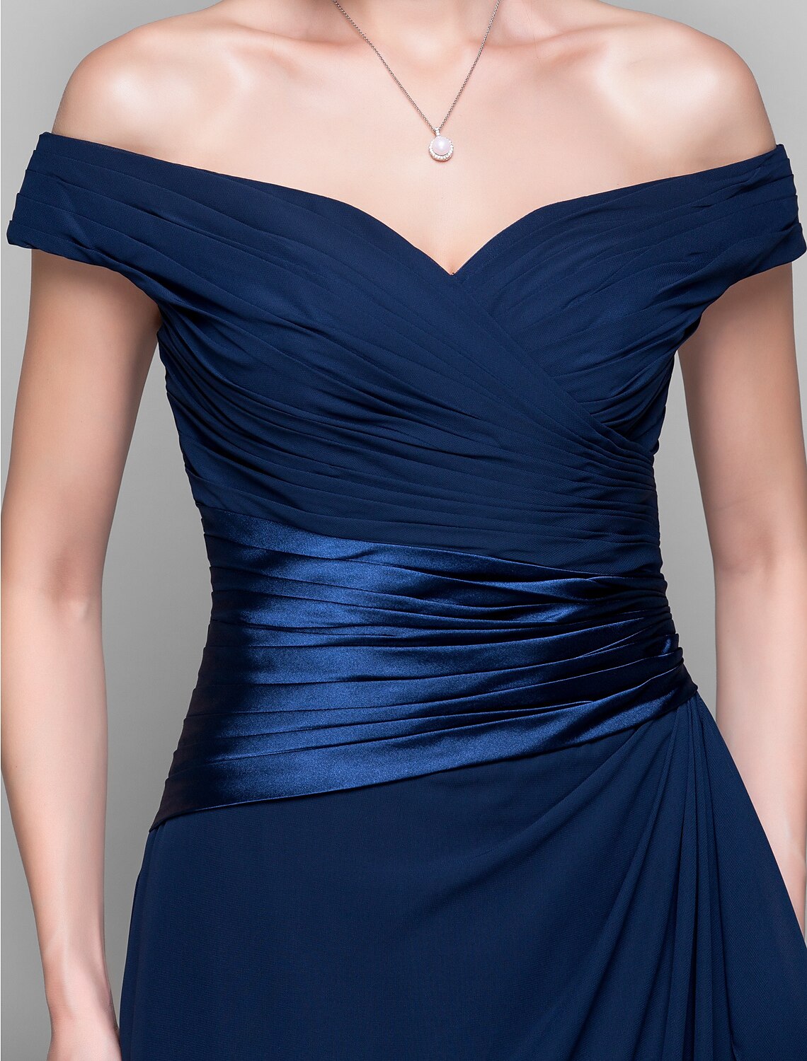 Woman posing in a dark blue off-shoulder sheath column dress, showcasing the floor-length design.