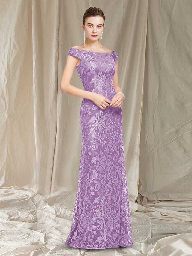 A woman wearing an elegant floor-length sheath column Mother of the Bride dress with a jewel neck and lace cap sleeves.
