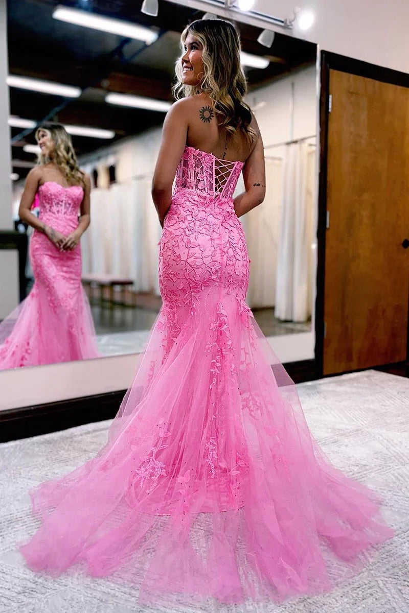 Woman wearing a blue sheath column prom gown with spaghetti straps and appliques.