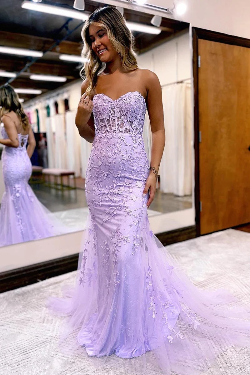 Woman wearing a pink sheath column prom gown with spaghetti straps and appliques.