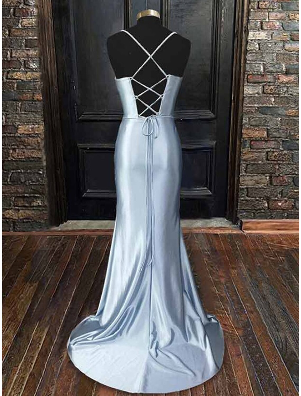 Side profile of a woman wearing a black satin sheath dress, highlighting the cowl neckline and flowing skirt.