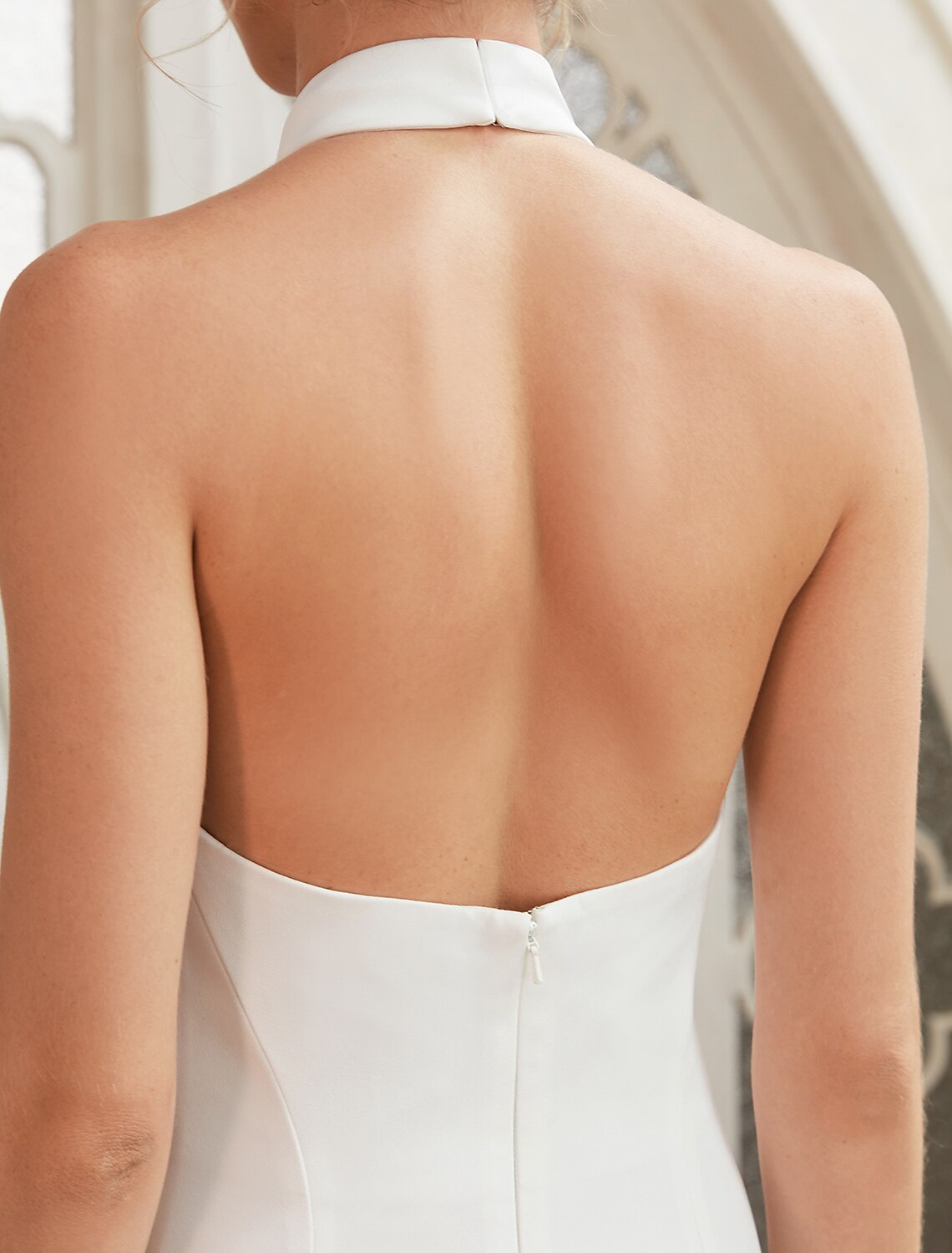 Detailed view of the halter strap and elegant neckline of the white satin dress.