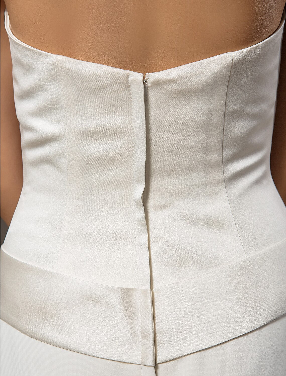 Close-up of satin fabric and sash detail on wedding dress.