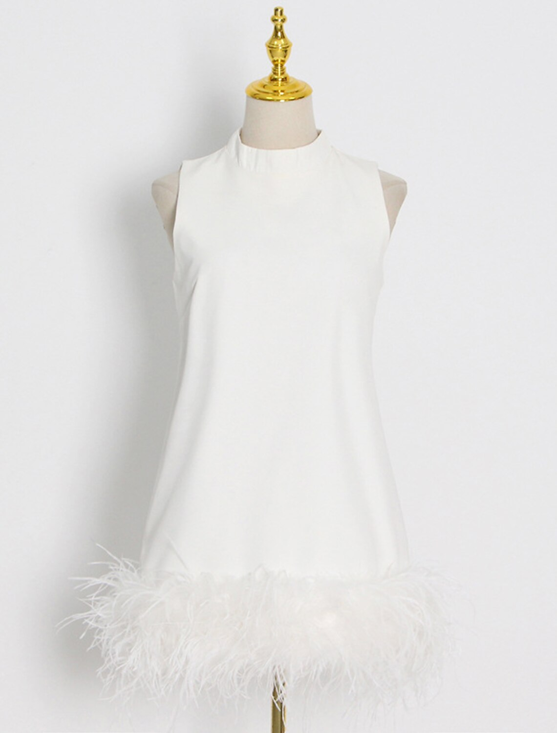 Close-up of feather embellishment on a white high neck dress.
