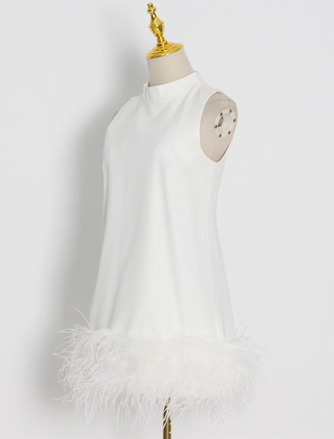 Full length view of an elegant white short dress with feather accents.