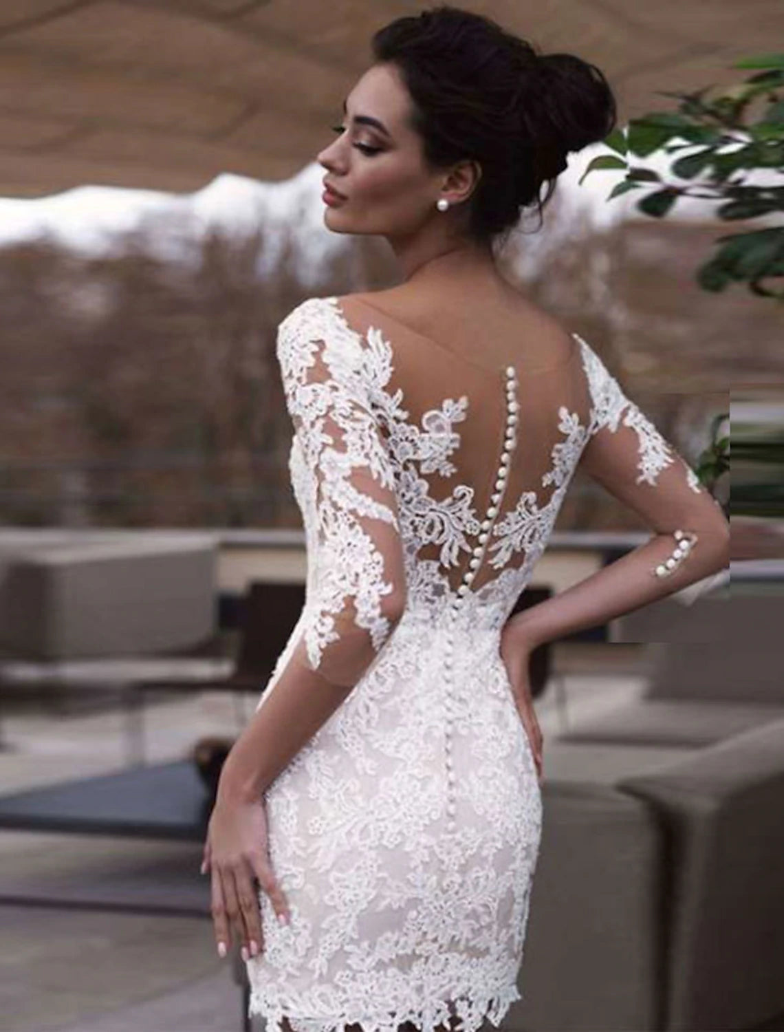 Side profile of a bride wearing a short white lace bridal gown.