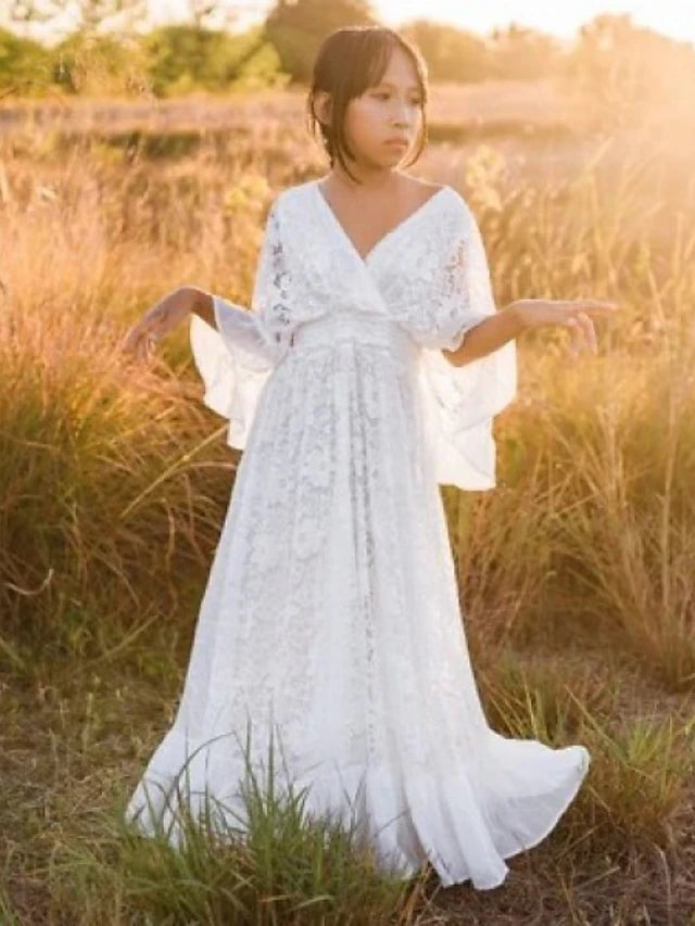 Flower girl in an ivory sheath lace dress, standing elegantly.