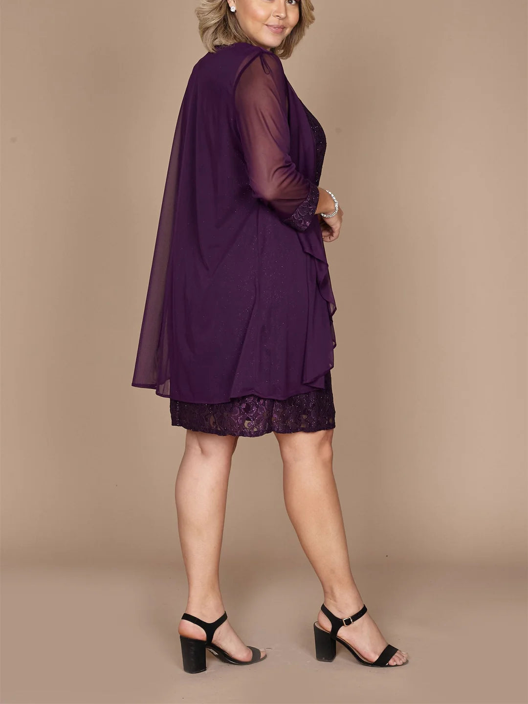 Woman modeling an elegant sheath dress with a lace neckline and short sleeves.